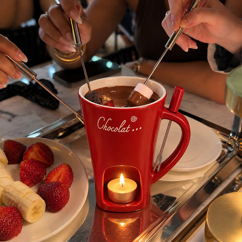 Fondue au chocolat entre amis : guimauve et fraise trempées dans le mug Fondora rouge chauffé à la bougie